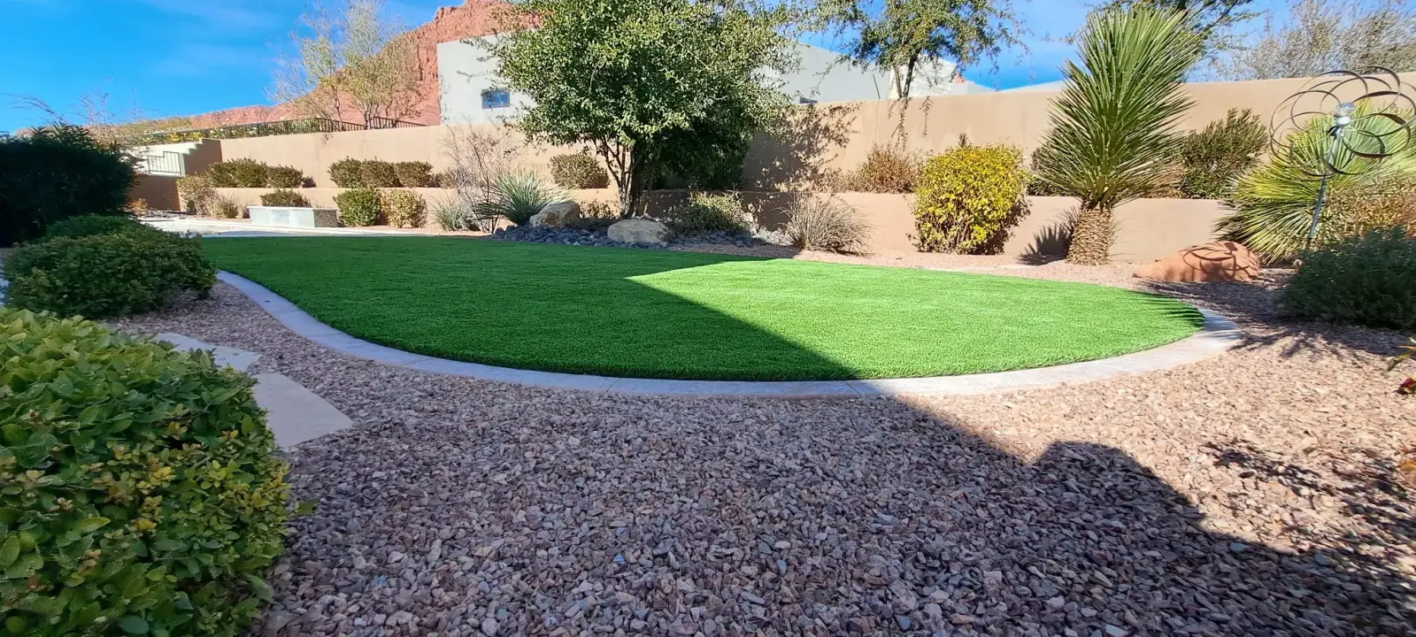 Turf lawn bordered by red rock gravel