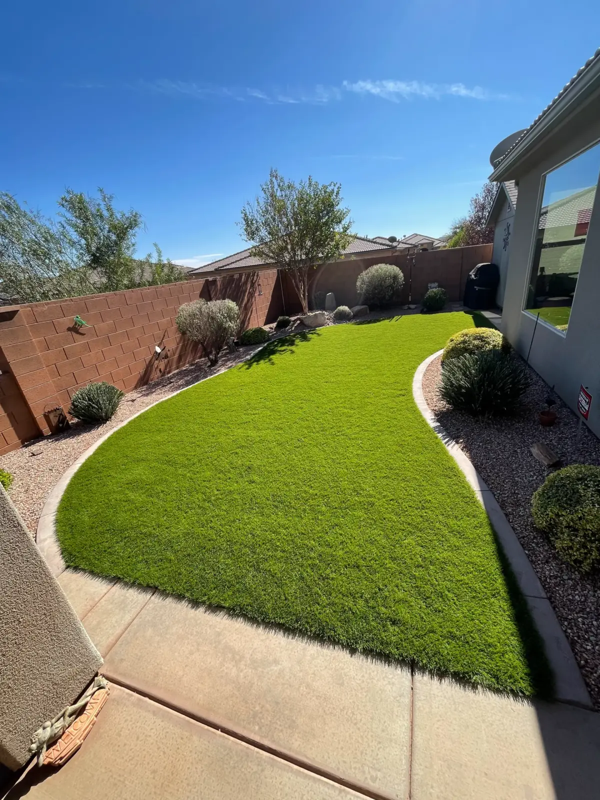 Backyard artificial turf with curved curbing along a block wall