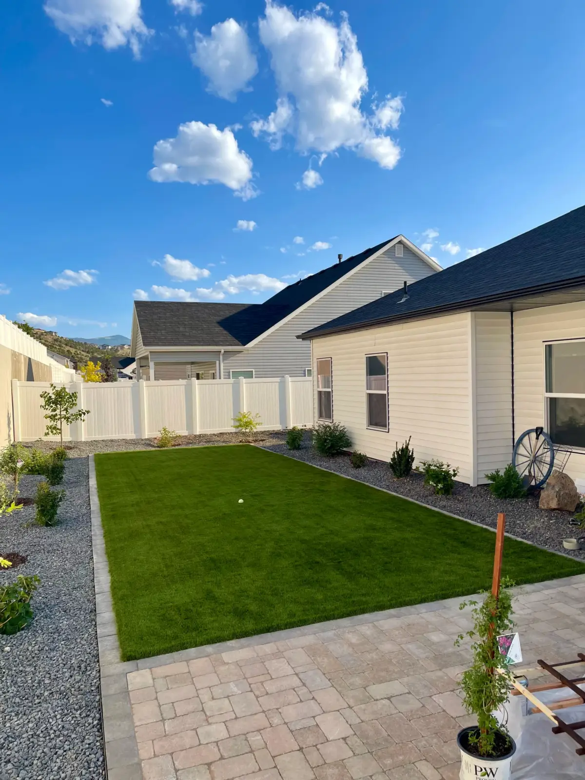 Rectangular backyard turf lawn with a white vinyl fence