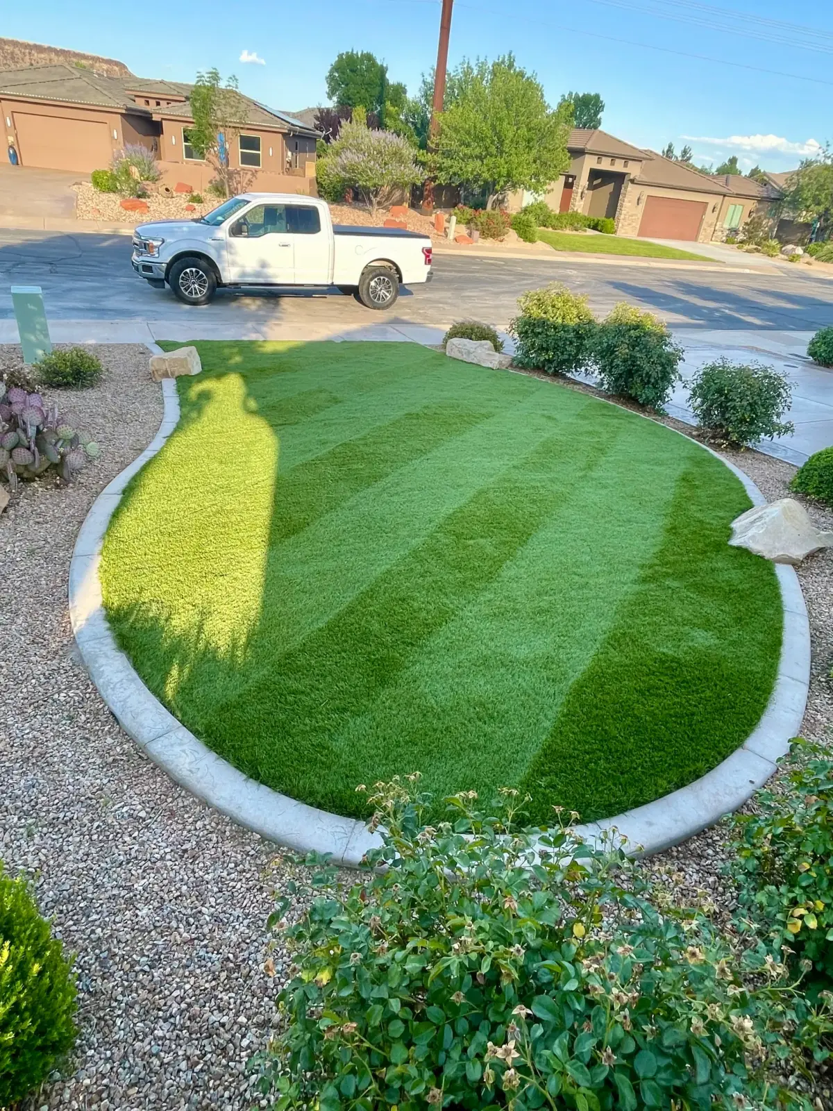Striped artificial turf front lawn with a curved concrete border